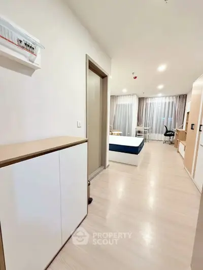 Modern studio apartment with sleek design and ample natural light, featuring a cozy bed and stylish furnishings.