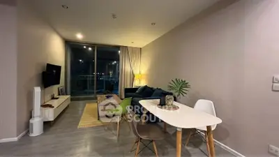 Modern living room with stylish furniture and large window offering a stunning night view.