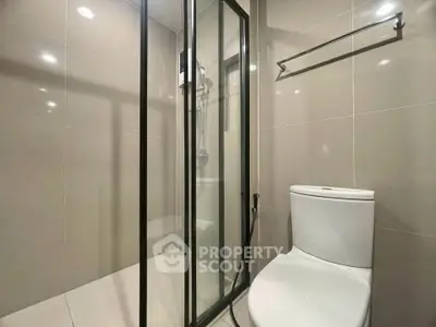 Modern bathroom with glass shower enclosure and sleek toilet design.