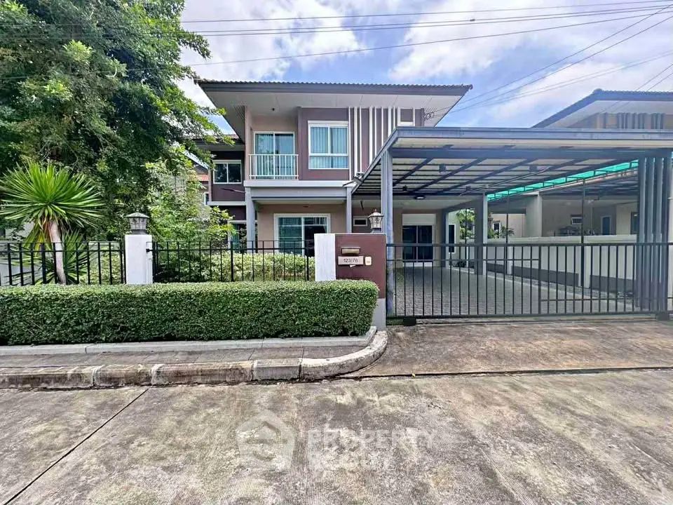 Modern two-story house with gated driveway and lush greenery