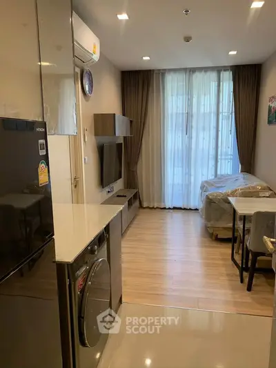 Modern apartment interior with open layout, featuring a cozy living area and sleek kitchen appliances.