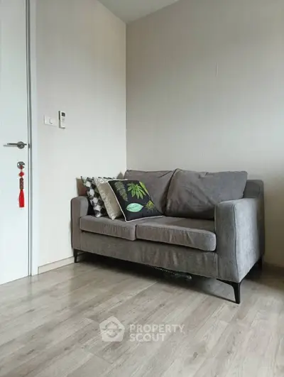 Cozy living room with modern gray sofa and decorative pillows on wooden flooring.