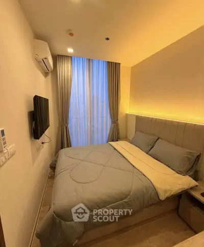 Cozy modern bedroom with city view, featuring elegant lighting and sleek furnishings.