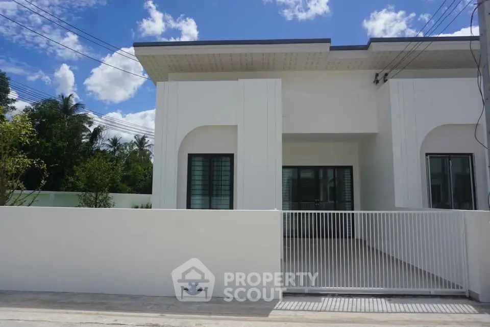 Modern white house exterior with gated entrance and clear blue sky