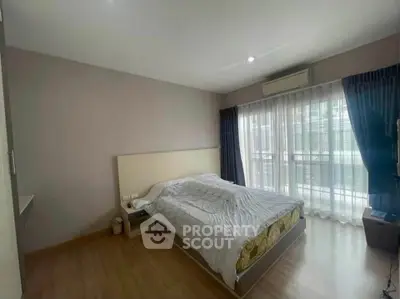 Spacious bedroom with large window and modern decor in a stylish apartment.