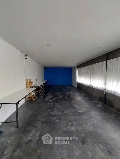 Spacious industrial-style room with concrete flooring and blue accent wall, ideal for creative workspace.