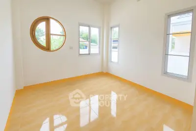 Bright empty room with unique round window and glossy tile flooring
