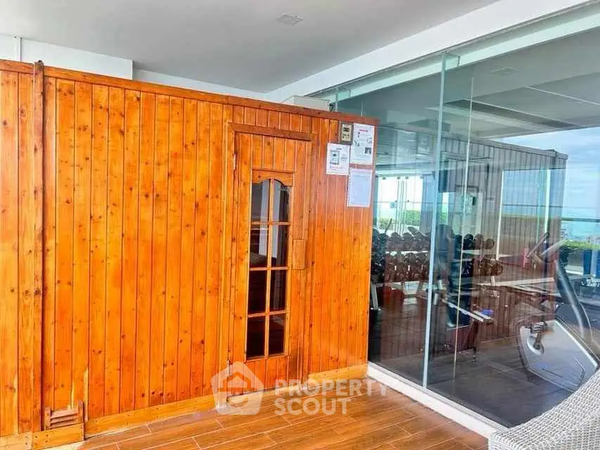 Luxurious rooftop gym with wooden sauna and glass walls offering stunning views.