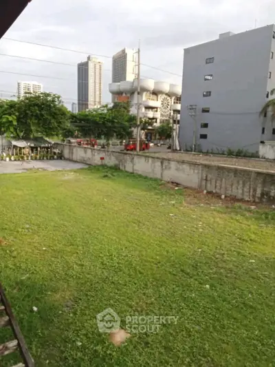 Spacious urban lot with lush greenery and cityscape backdrop, ideal for development.