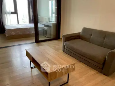Modern studio apartment with cozy living area and bedroom, featuring wooden flooring and large windows.