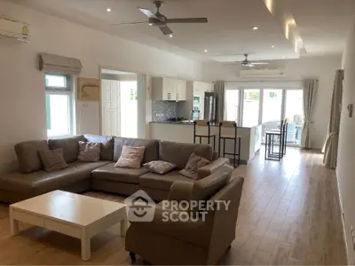 Spacious modern living room with open kitchen, featuring cozy seating and natural light.
