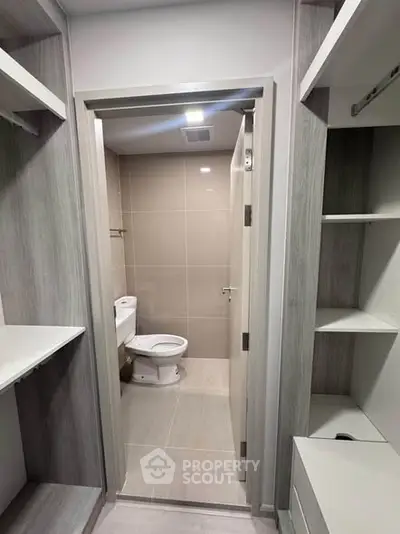 Modern bathroom with sleek design and neutral tones, featuring a toilet and built-in shelving.