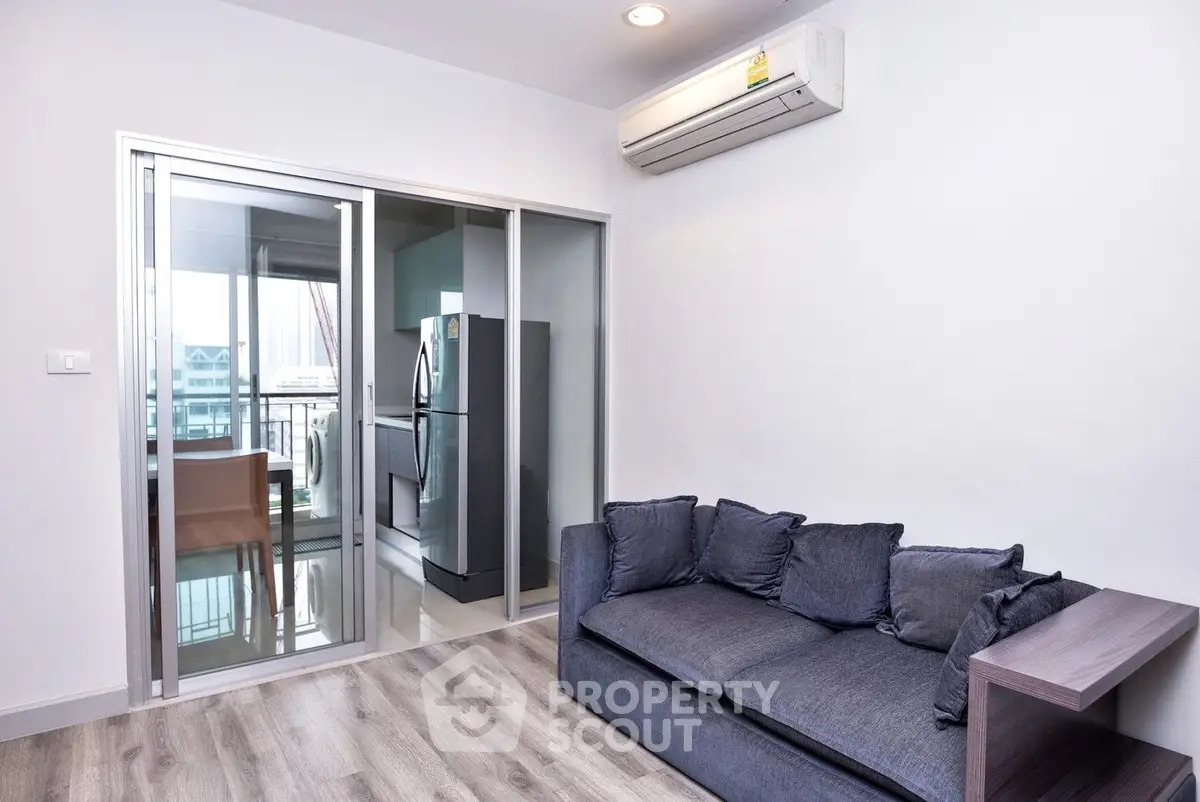 Modern living room with sleek sofa and balcony view, perfect for urban living.