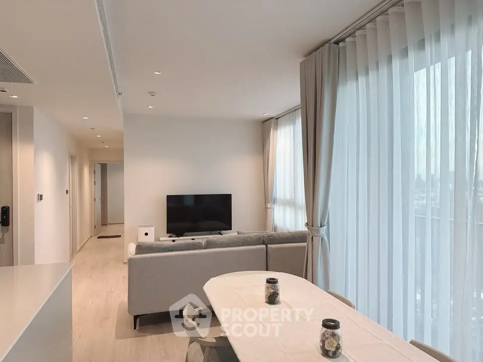 Modern living room with large windows and elegant decor in a high-rise apartment.