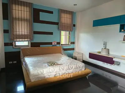 Spacious modern bedroom with stylish decor and large windows for natural light.