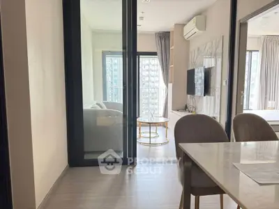 Modern apartment interior with open living room and dining area, featuring stylish furniture and large windows.