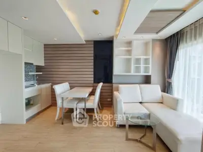 Modern open-layout living room with stylish kitchen and dining area, featuring elegant furniture and natural light.
