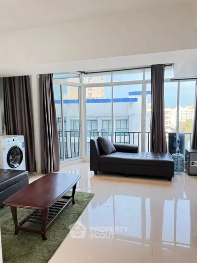 Spacious living room with modern furniture and large windows offering city views.