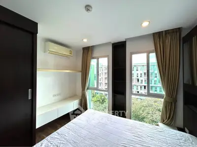 Bright bedroom with large windows and modern furnishings in a high-rise apartment.