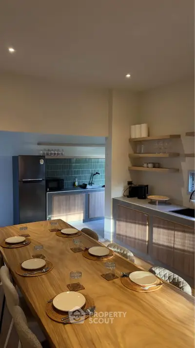 Modern kitchen with open layout and dining area, featuring sleek appliances and wooden accents.