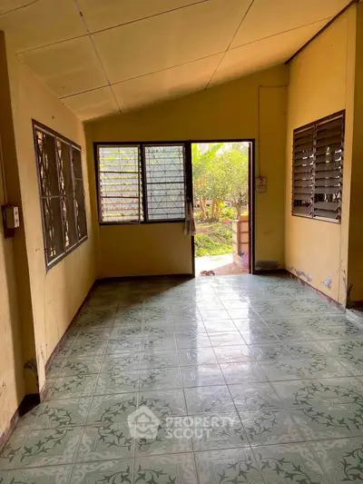 Spacious room with tiled floor and large windows offering garden view.