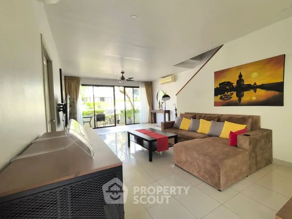 Spacious living room with modern decor and large windows opening to a balcony, perfect for relaxation.