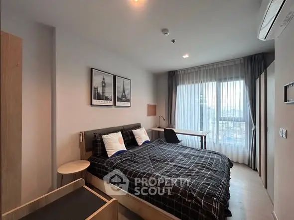 Modern bedroom with stylish decor and large window offering natural light.