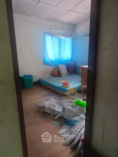 Unfurnished bedroom with potential for renovation, featuring natural light and wooden flooring.