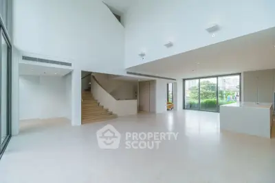 Spacious modern living room with open layout and large windows offering garden views.