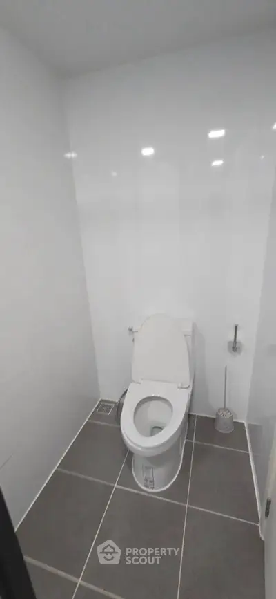 Modern minimalist bathroom with sleek white tiles and contemporary toilet design.