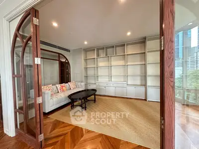 Spacious living room with elegant wooden flooring and built-in shelves.