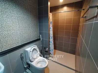 Modern bathroom with sleek tiles and shower area in contemporary home.
