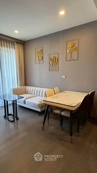 Elegant living room with modern decor and dining area, featuring stylish furniture and wall art.