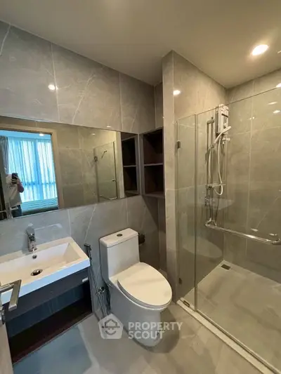 Modern bathroom with sleek design, featuring a glass shower enclosure and stylish fixtures.