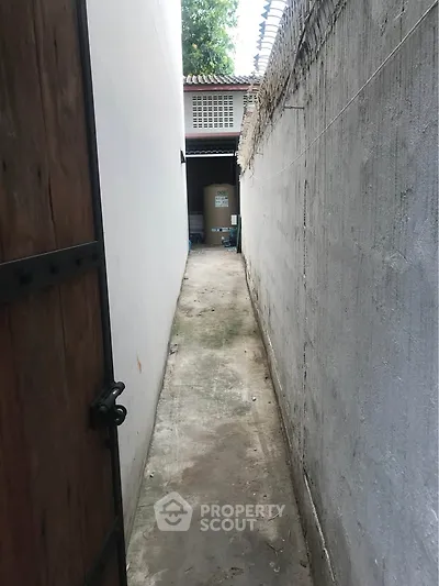 Narrow alleyway leading to a storage area with a secure gate.