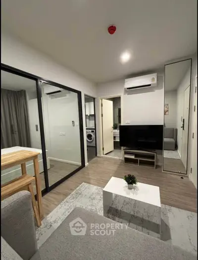 Modern living room with sleek design and glass partition, featuring air conditioning and stylish decor.