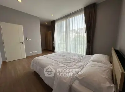 Spacious bedroom with large window and elegant decor in modern home