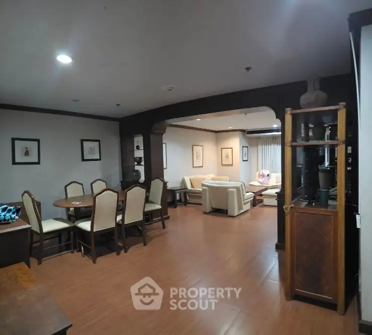 Spacious living and dining area with elegant furniture and wooden flooring.