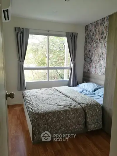 Cozy bedroom with large window and stylish decor, perfect for relaxation and comfort.