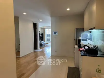 Modern apartment interior with open layout, featuring a sleek kitchen and spacious living area with wooden flooring.