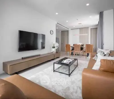 Spacious modern living room with leather sofas and large TV, perfect for relaxation and entertainment.