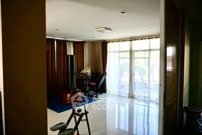 Spacious living room with exercise equipment and large windows for natural light.