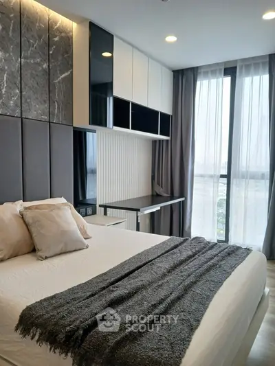 Modern bedroom with stylish decor and large windows offering natural light.