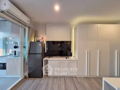 Modern living room with sleek furniture and large TV, featuring a stylish open layout.