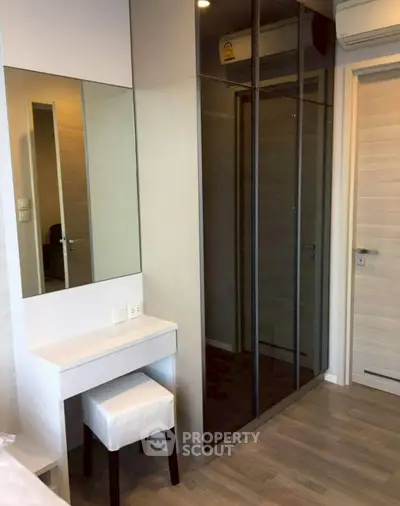 Modern bedroom with sleek mirrored wardrobe and compact vanity area.