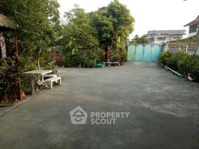 Spacious garden area with lush greenery and paved driveway