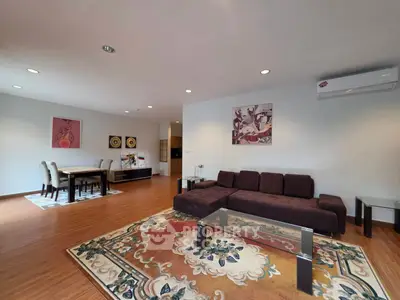 Spacious living room with elegant decor and dining area, featuring modern furniture and wooden flooring.