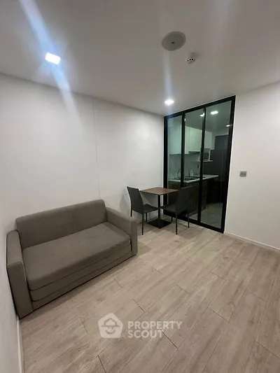 Modern living room with sleek design and open kitchen layout, featuring a cozy sofa and dining area.