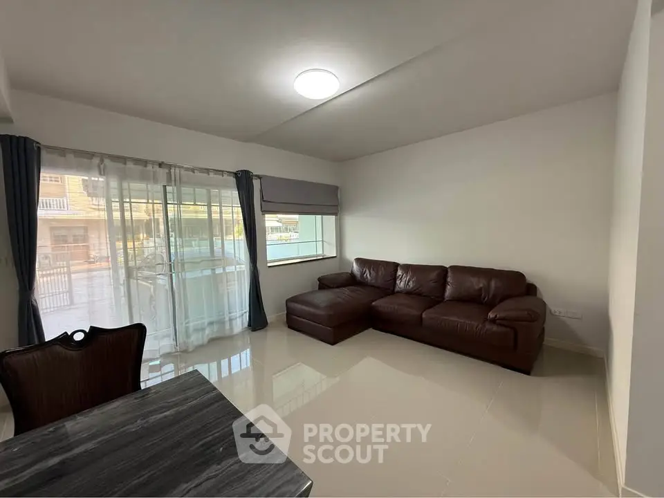 Spacious living room with modern leather sofa and large windows for natural light.