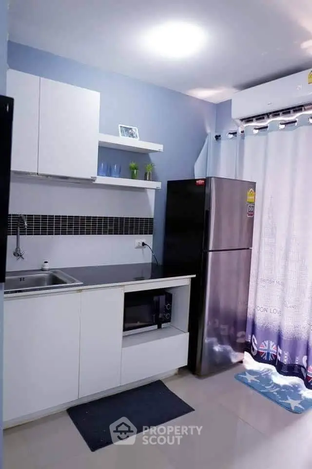 Modern kitchen with sleek cabinetry and stainless steel appliances in a cozy apartment.